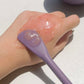 Applying gel-textured skincare product on the back of the hand using the flat side of a purple silicone spatula