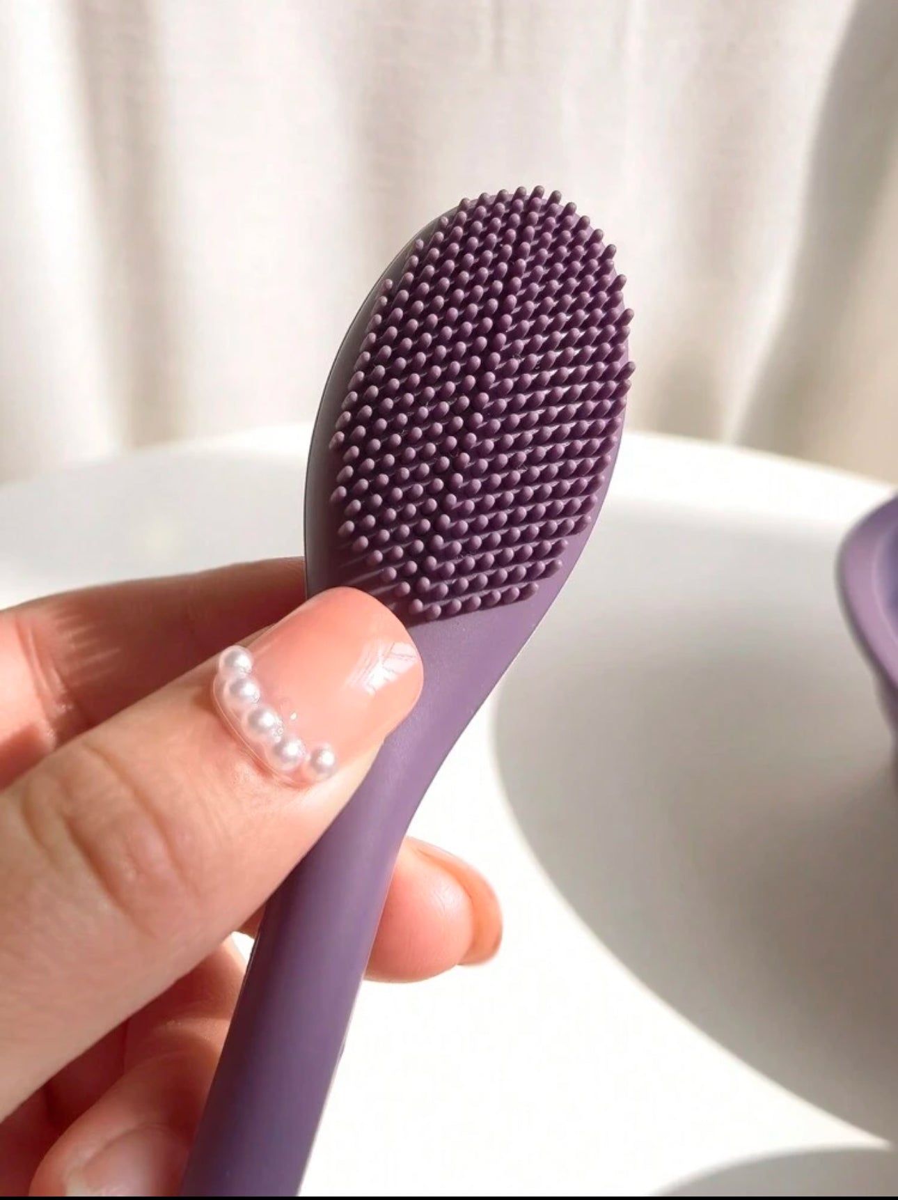 Close-up of the soft silicone bristle side of a dual-ended purple face cleansing brush