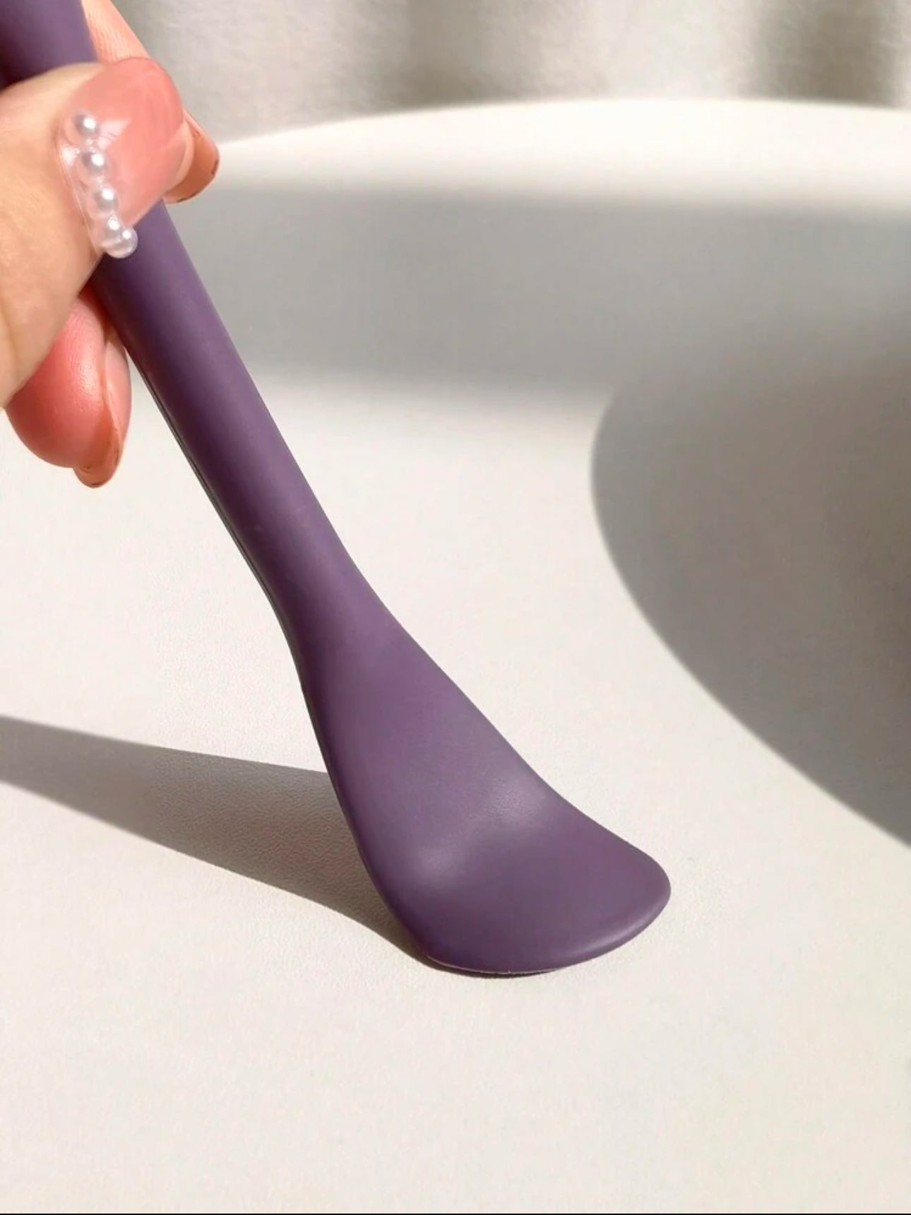 Close-up of the flat applicator side of a purple dual-ended silicone skincare tool